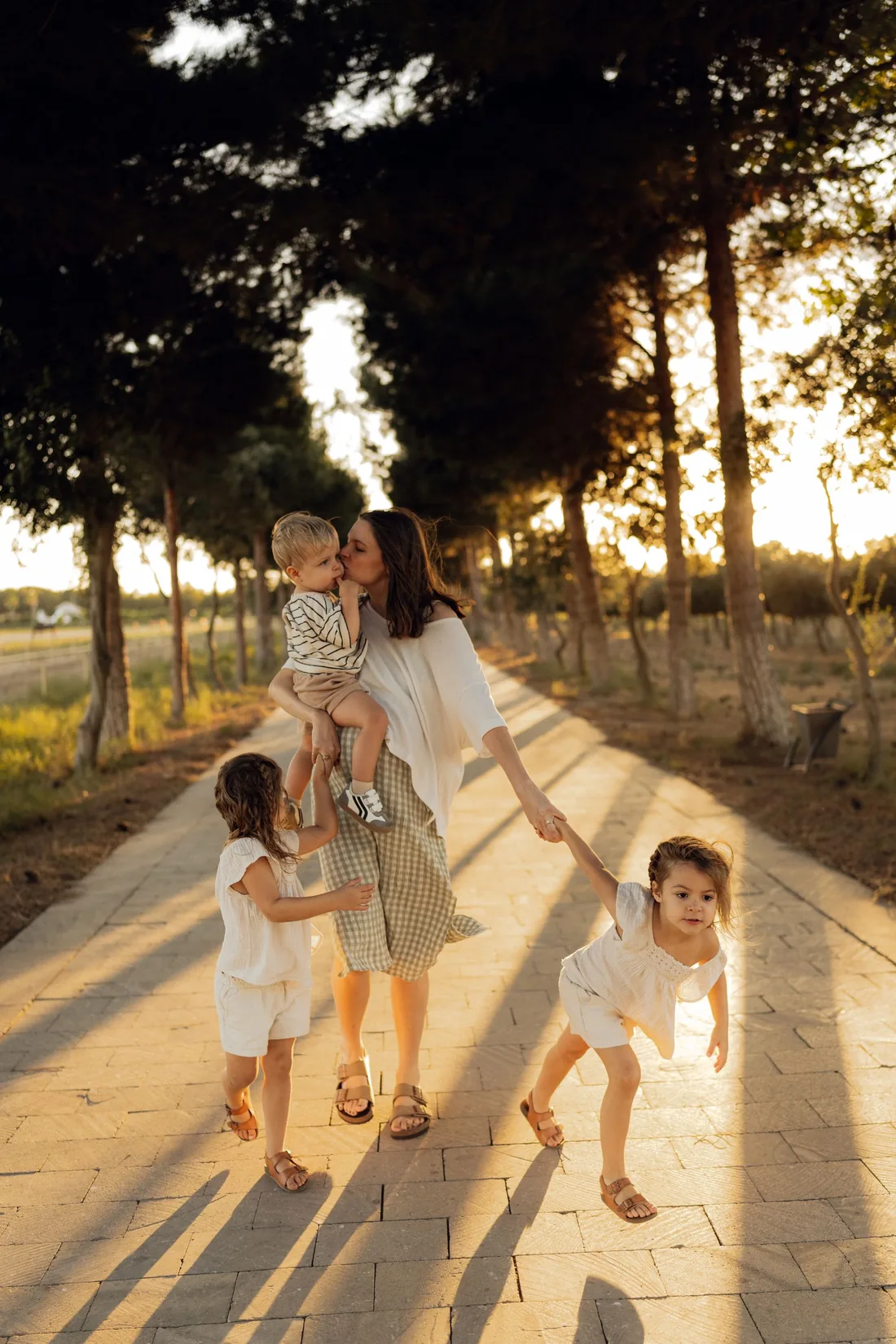 A parent enjoying a sunlit walk with three children
